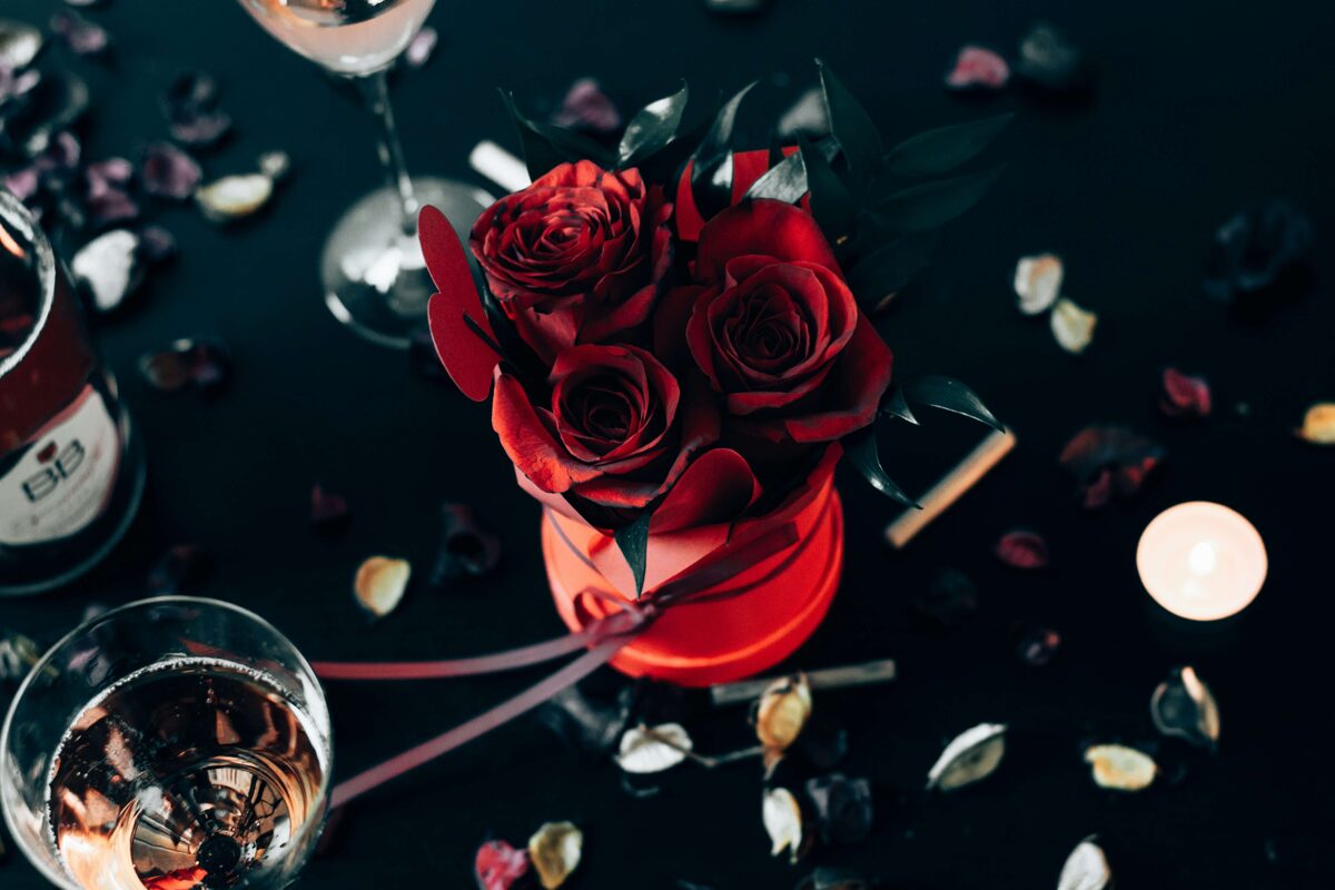 a bouquet of red roses and a glass of rose wine