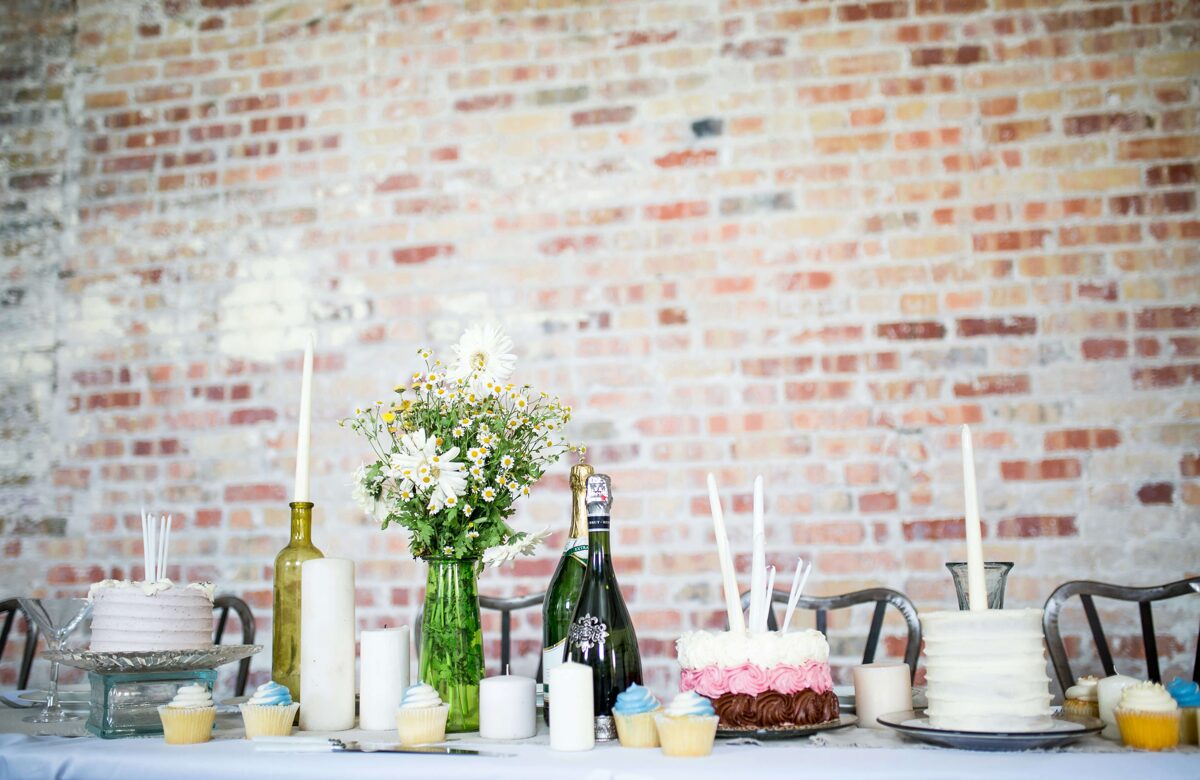 wedding cake, candles and a bottle of sparkling wine on a table